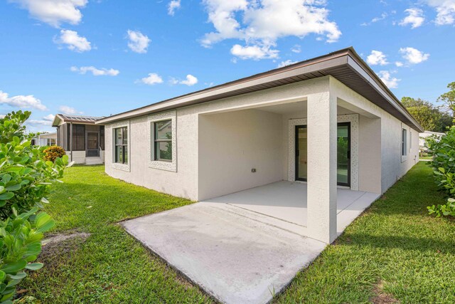 15093 Aguila Ave, Fort Pierce, FL 34951 - rear view of property with a patio area, a sunroom, and a lawn