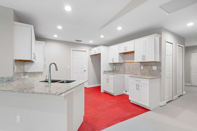 15093 Aguila Ave, Fort Pierce, FL 34951 - kitchen featuring white cabinetry, sink, kitchen peninsula, light stone countertops, and backsplash