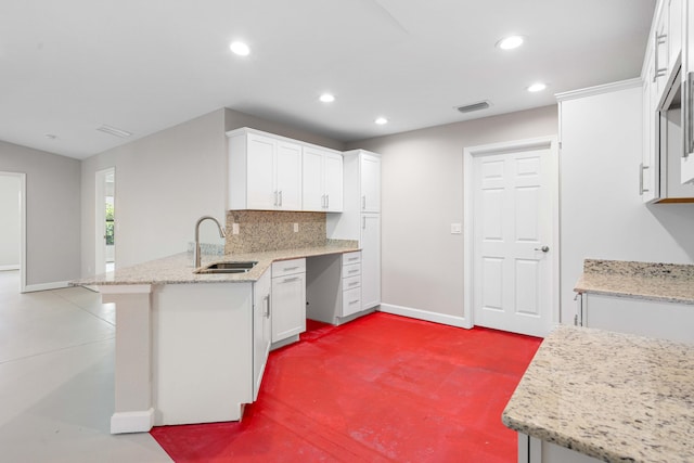 15093 Aguila Ave, Fort Pierce, FL 34951 - kitchen with light stone counters, white cabinets, kitchen peninsula, sink, and backsplash
