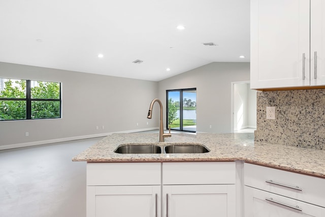15093 Aguila Ave, Fort Pierce, FL 34951 - kitchen with vaulted ceiling, white cabinets, sink, backsplash, and light stone countertops