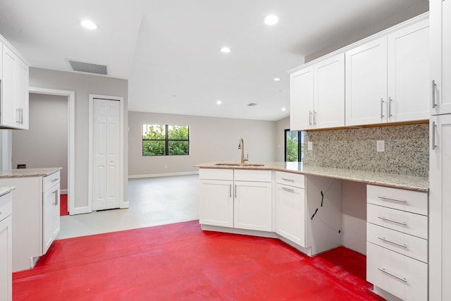 15093 Aguila Ave, Fort Pierce, FL 34951 - kitchen featuring sink, kitchen peninsula, light stone countertops, backsplash, and white cabinets