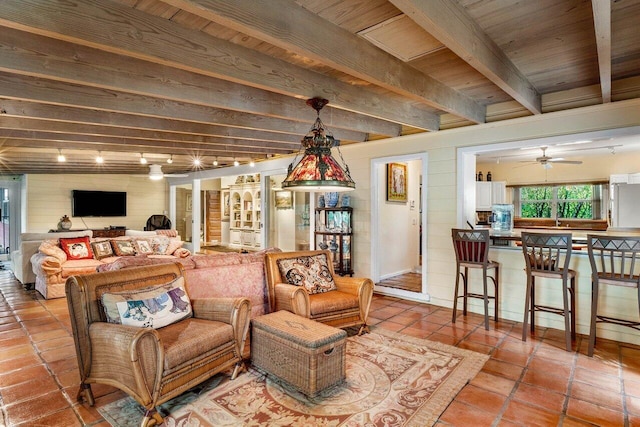 living area with tile patterned flooring, rail lighting, beamed ceiling, wooden ceiling, and ceiling fan