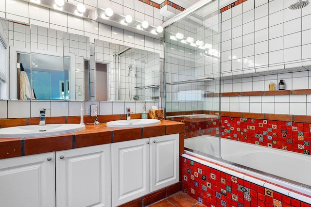 bathroom with tile walls, bath / shower combo with glass door, tile patterned flooring, and vanity