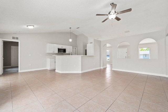 unfurnished living room with ceiling fan, vaulted ceiling, and light tile patterned floors