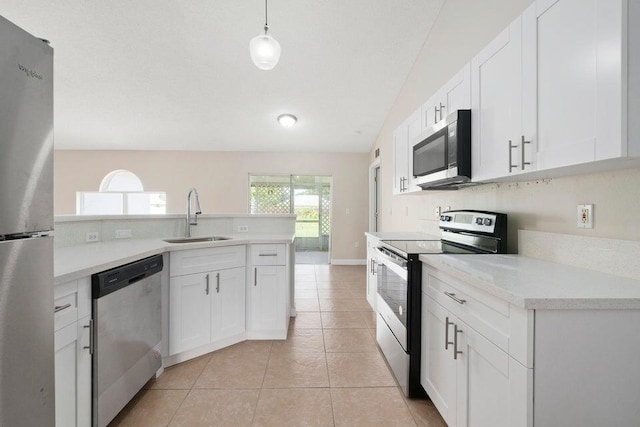 kitchen with stainless steel appliances, white cabinets, sink, light tile patterned flooring, and decorative light fixtures