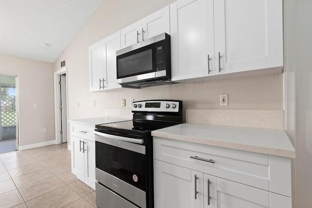 kitchen with stainless steel appliances, white cabinetry, a textured ceiling, light tile patterned floors, and vaulted ceiling