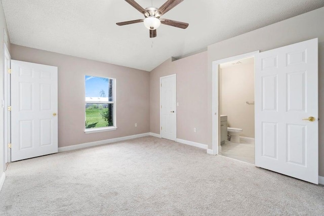 unfurnished bedroom with ceiling fan, ensuite bath, light carpet, and lofted ceiling