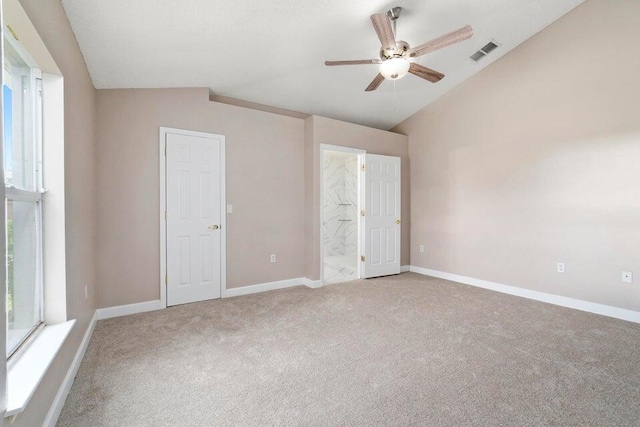 unfurnished bedroom with carpet flooring, ceiling fan, vaulted ceiling, and connected bathroom