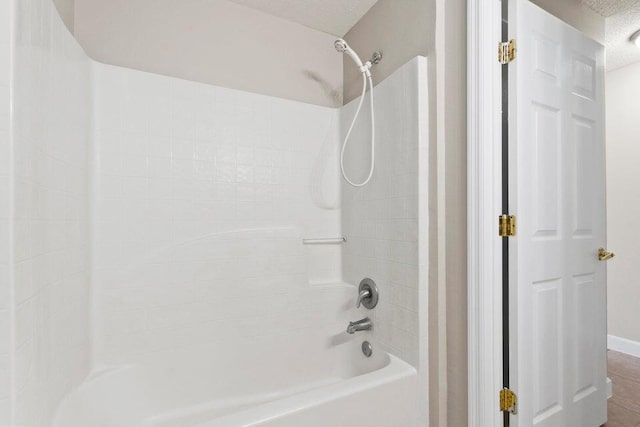 bathroom featuring a textured ceiling and bathtub / shower combination