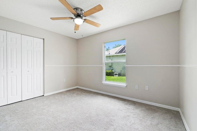 unfurnished bedroom with ceiling fan, a textured ceiling, carpet flooring, and a closet