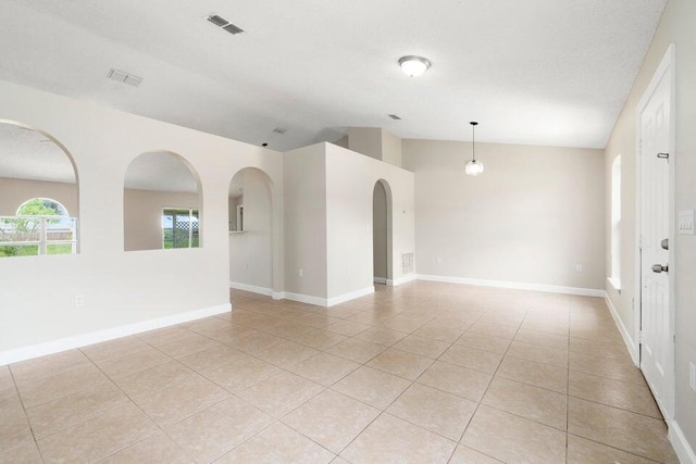 unfurnished room featuring lofted ceiling and light tile patterned flooring