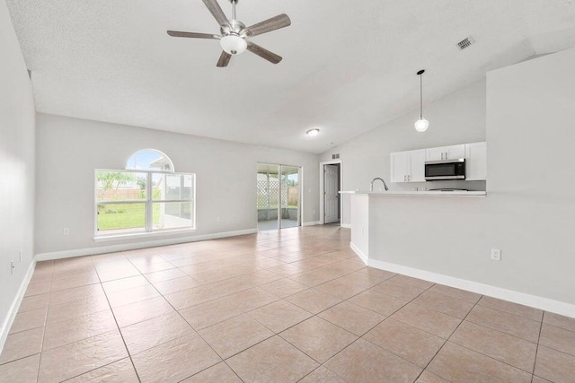 unfurnished living room featuring a textured ceiling, high vaulted ceiling, light tile patterned floors, and ceiling fan