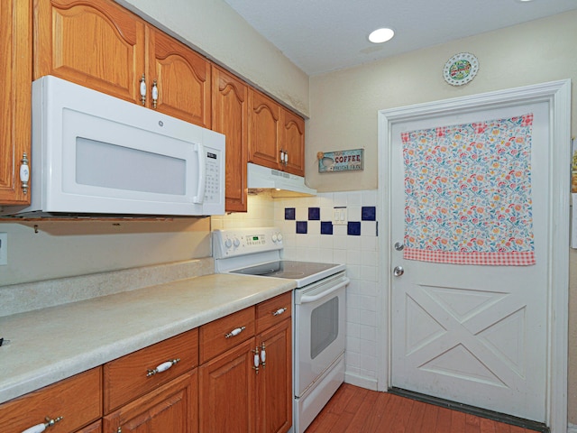 kitchen featuring hardwood / wood-style floors, white appliances, and backsplash