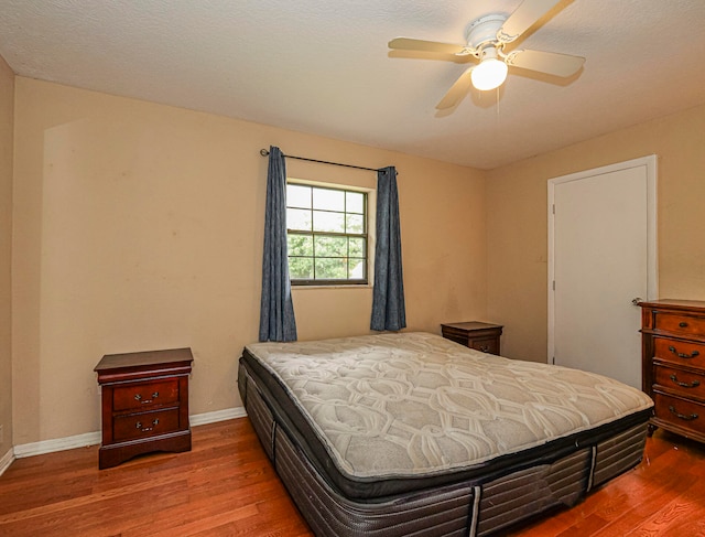 bedroom with ceiling fan, a textured ceiling, and hardwood / wood-style flooring