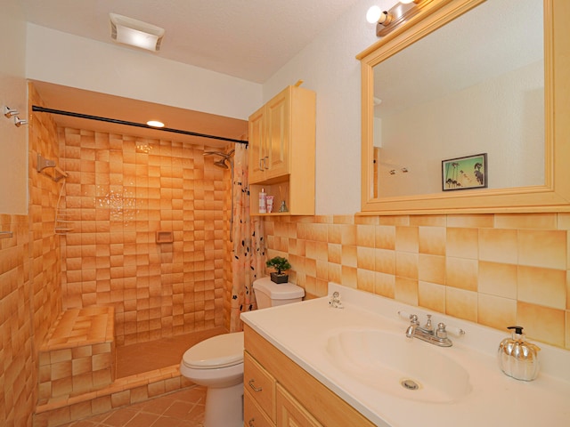 bathroom featuring tile patterned flooring, toilet, tiled shower, vanity, and tile walls