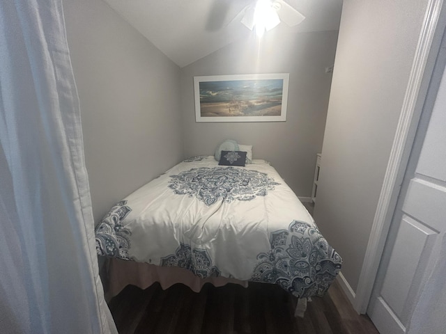 bedroom with ceiling fan, dark wood-type flooring, and vaulted ceiling