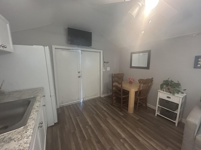 dining space with ceiling fan, sink, dark wood-type flooring, and vaulted ceiling