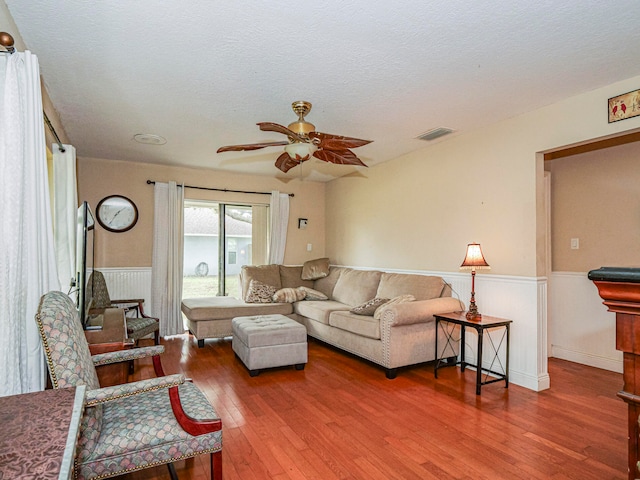 living room with hardwood / wood-style floors, ceiling fan, and a textured ceiling