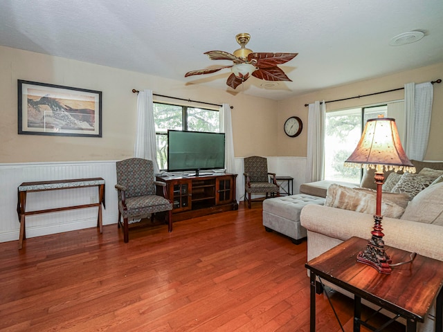 living room with hardwood / wood-style flooring, ceiling fan, and a textured ceiling