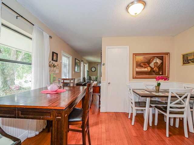 dining area with light hardwood / wood-style floors and a textured ceiling