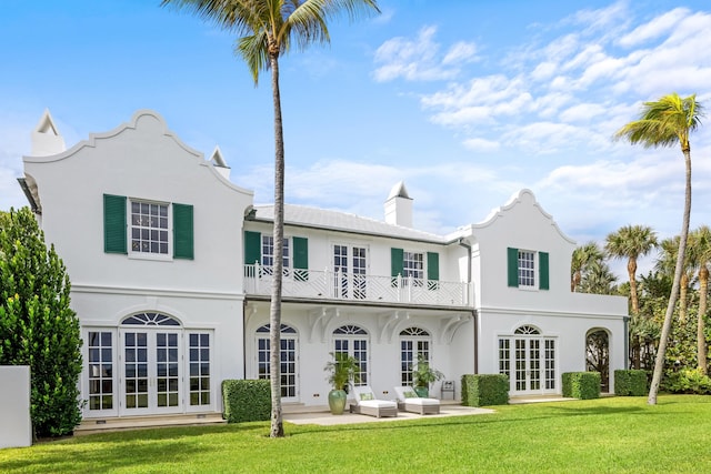 back of house featuring french doors, an outdoor hangout area, a balcony, a patio area, and a lawn