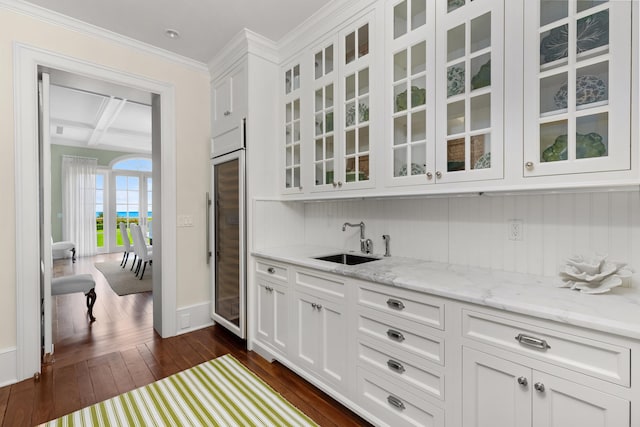 bar with dark wood finished floors, ornamental molding, a sink, coffered ceiling, and baseboards