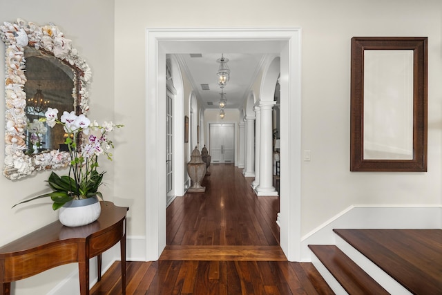 corridor featuring dark hardwood / wood-style flooring, crown molding, and decorative columns