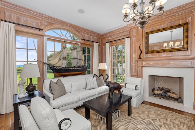 living room featuring wood walls, a healthy amount of sunlight, light wood-type flooring, and an inviting chandelier