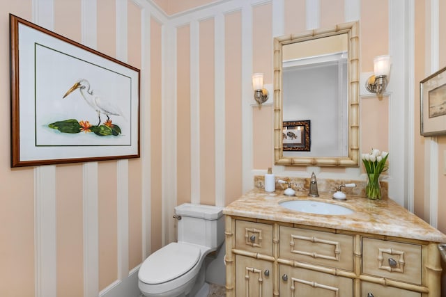 bathroom featuring toilet, wallpapered walls, and vanity