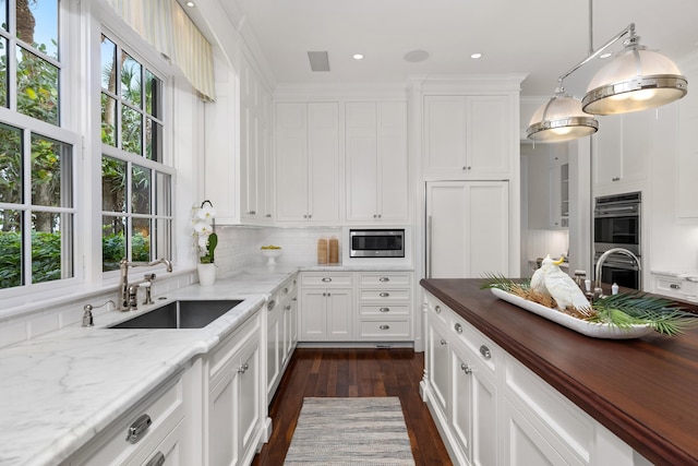 kitchen featuring plenty of natural light, sink, stainless steel appliances, and wooden counters