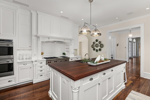 kitchen featuring wooden counters, a center island, white cabinetry, and dark wood-type flooring