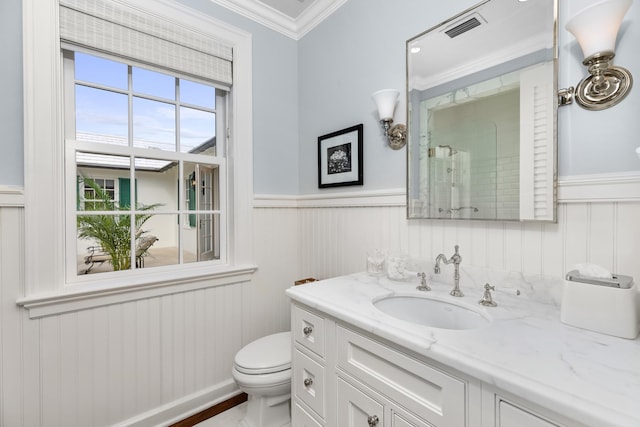 bathroom featuring toilet, a wainscoted wall, vanity, visible vents, and crown molding