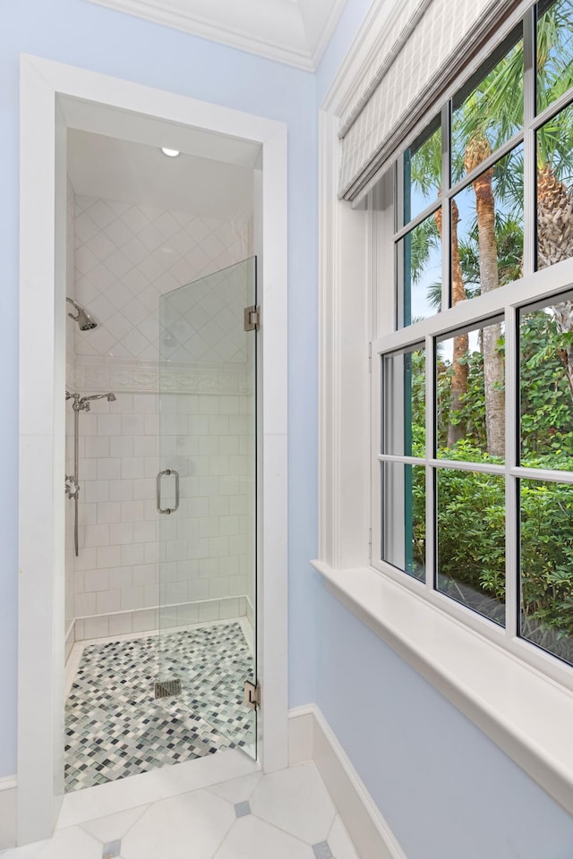 bathroom with tile patterned flooring, a wealth of natural light, ornamental molding, and walk in shower