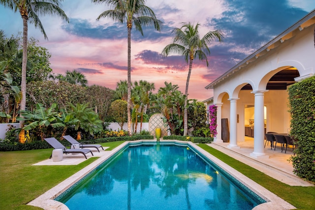 pool at dusk with a lawn and a patio