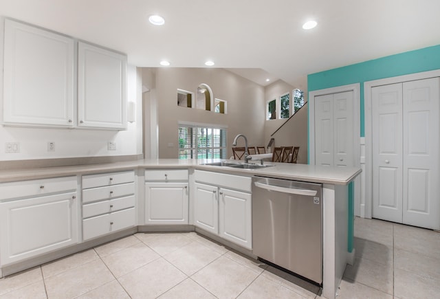 kitchen with dishwasher, white cabinets, sink, light tile patterned floors, and kitchen peninsula