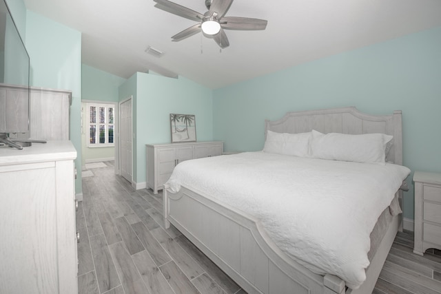 bedroom featuring a closet, light hardwood / wood-style flooring, vaulted ceiling, and ceiling fan