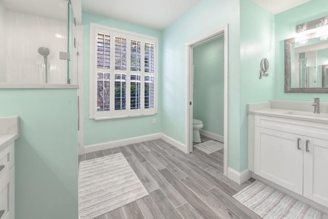 bathroom featuring vanity, hardwood / wood-style flooring, toilet, and walk in shower