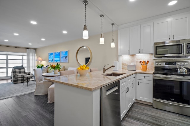 kitchen with stainless steel appliances, white cabinetry, dark hardwood / wood-style flooring, sink, and kitchen peninsula