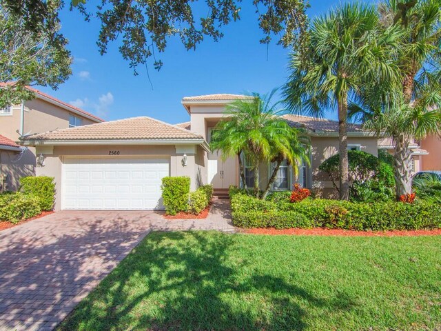 mediterranean / spanish home featuring a front lawn and a garage