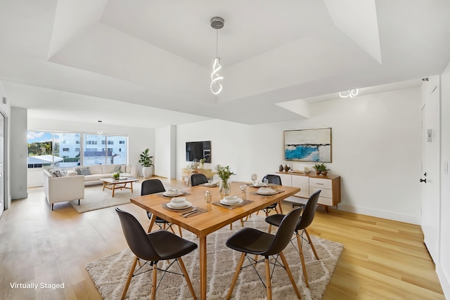 dining room with light hardwood / wood-style floors and a tray ceiling