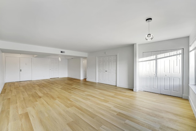 unfurnished bedroom featuring multiple closets and light wood-type flooring