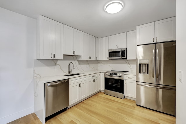 kitchen featuring white cabinetry, sink, stainless steel appliances, and light hardwood / wood-style floors