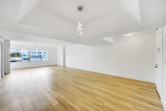 unfurnished living room featuring a tray ceiling and light wood-type flooring