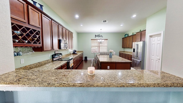 kitchen with light stone counters, stainless steel appliances, a notable chandelier, pendant lighting, and kitchen peninsula