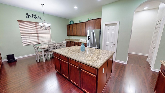 kitchen with hanging light fixtures, stainless steel fridge with ice dispenser, dark hardwood / wood-style flooring, and a center island