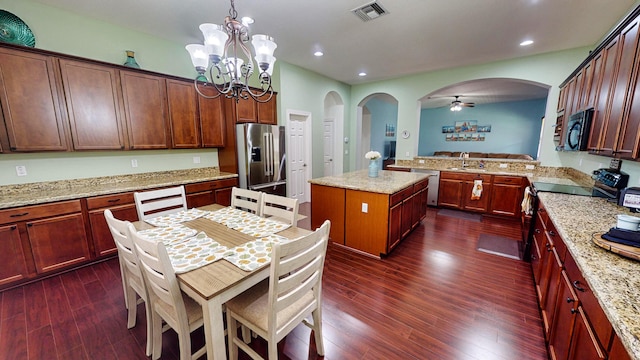 kitchen featuring appliances with stainless steel finishes, kitchen peninsula, a kitchen island, dark wood-type flooring, and pendant lighting