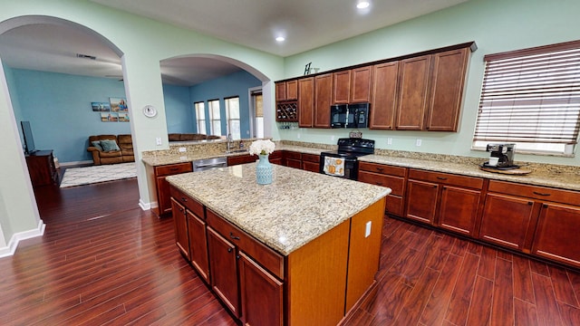 kitchen with black appliances, a kitchen island, dark wood-type flooring, and light stone counters