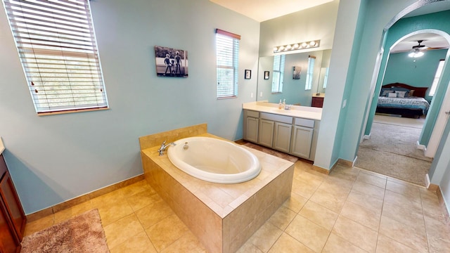 bathroom with a relaxing tiled tub, ceiling fan, vanity, and tile patterned floors