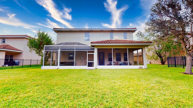 rear view of house featuring glass enclosure, a sunroom, and a yard