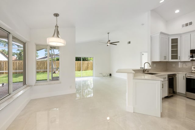 kitchen featuring white cabinets, kitchen peninsula, high vaulted ceiling, and sink